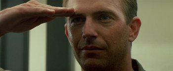 Movie still from “Revenge” (1990), directed by Tony Scott – A person saluting with one hand; Close Up shot, Low angle