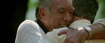 Movie still from “Revenge” (1990), directed by Tony Scott – An older man is holding a baby in his arms; Close Up shot, Over the shoulder angle