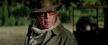 Movie still from “Revenge” (1990), directed by Tony Scott – An older man wearing a hat and a scarf; Close Up shot, Low angle