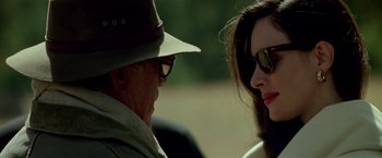Movie still from “Revenge” (1990), directed by Tony Scott – An older man and a younger woman wearing sunglasses; Close Up shot, Over the shoulder angle