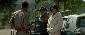 Movie still from “Revenge” (1990), directed by Tony Scott – A group of people standing next to each other near trees; Medium shot, Low angle