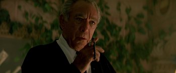 Movie still from “Revenge” (1990), directed by Tony Scott – An older man wearing a suit and tie holding a cell phone to his ear; Close Up shot, Low angle