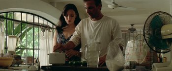Movie still from “Revenge” (1990), directed by Tony Scott – A man and a woman preparing food on a counter; Medium shot, Low angle