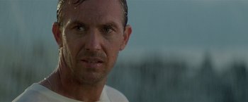 Movie still from “Revenge” (1990), directed by Tony Scott – A man's face with water droplets on his face; Close Up shot, Low angle