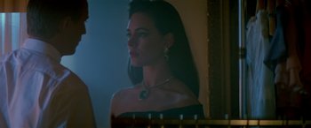 Movie still from “Revenge” (1990), directed by Tony Scott – A beautiful woman with long dark hair wearing a black dress; Close Up shot, Over the shoulder angle