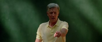 Movie still from “Revenge” (1990), directed by Tony Scott – An older man in a yellow shirt is pointing; Medium shot, Low angle