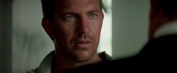 Movie still from “Revenge” (1990), directed by Tony Scott – A man's face with green eyes; Close Up shot, Over the shoulder angle