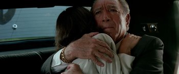 Movie still from “Revenge” (1990), directed by Tony Scott – An older man hugging a younger woman in the back of a car; Close Up shot, Low angle