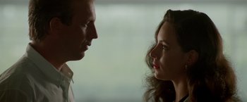 Movie still from “Revenge” (1990), directed by Tony Scott – A man and a woman face to face in front of a window; Close Up shot, Low angle