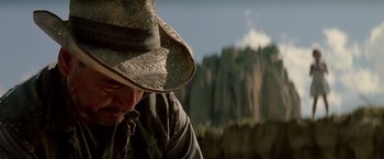 Movie still from “Revenge” (1990), directed by Tony Scott – A man wearing a cowboy hat in front of a mountain range; Close Up shot, Low angle
