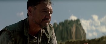 Movie still from “Revenge” (1990), directed by Tony Scott – A person with a mountain in the background; Close Up shot, Over the shoulder angle