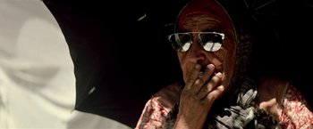 Movie still from “Revenge” (1990), directed by Tony Scott – An older man smoking a cigarette while sitting in a car; Close Up shot, Low angle