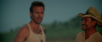 Movie still from “Revenge” (1990), directed by Tony Scott – A person wearing a tank top; Close Up shot, Low angle