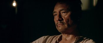 Movie still from “Revenge” (1990), directed by Tony Scott – An older man is looking at the camera; Close Up shot, Low angle