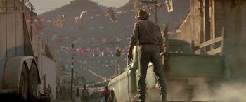 Movie still from “Revenge” (1990), directed by Tony Scott – A man standing on the side of a train; Wide shot, Low angle