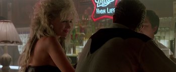 Movie still from “Revenge” (1990), directed by Tony Scott – A woman standing next to a man at a bar; Close Up shot, Over the shoulder angle