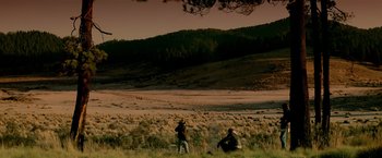 Movie still from “Revenge” (1990), directed by Tony Scott – Two people are standing in a field near a hill; Extreme Wide shot, High angle