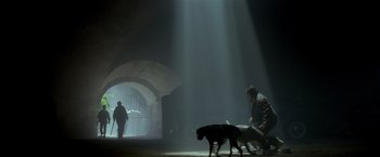 Movie still from “Revenge” (1990), directed by Tony Scott – A man and a dog walking through a tunnel; Wide shot, Low angle