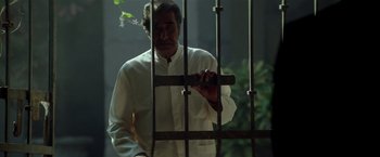 Movie still from “Revenge” (1990), directed by Tony Scott – An old man in a white shirt is behind bars; Medium shot, Low angle