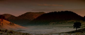 Movie still from “Revenge” (1990), directed by Tony Scott – A large body of water near a wooded area; Extreme Wide shot, High angle