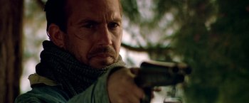 Movie still from “Revenge” (1990), directed by Tony Scott – A person holding a gun; Close Up shot, Low angle