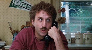 Movie still from “Reversal of Fortune” (1990), directed by Barbet Schroeder – A man with curly hair talking on a phone; Close Up shot, Over the shoulder angle