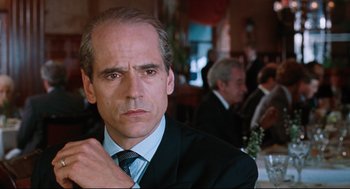 Movie still from “Reversal of Fortune” (1990), directed by Barbet Schroeder – A person wearing a suit and tie; Close Up shot, Over the shoulder angle