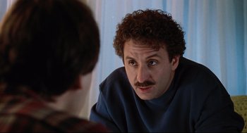 Movie still from “Reversal of Fortune” (1990), directed by Barbet Schroeder – A man with curly hair and a mustache is looking at a man in a blue shirt; Close Up shot, Over the shoulder angle