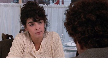 Movie still from “Reversal of Fortune” (1990), directed by Barbet Schroeder – A woman sitting in front of another woman in front of a table; Close Up shot, Over the shoulder angle