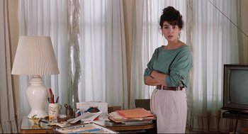 Movie still from “Reversal of Fortune” (1990), directed by Barbet Schroeder – A woman standing in front of a table with papers; Medium shot, Over the shoulder angle