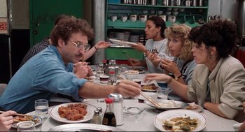 Movie still from “Reversal of Fortune” (1990), directed by Barbet Schroeder – A group of people sitting at a table eating food; Medium shot, Over the shoulder angle