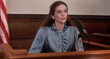 Movie still from “Reversal of Fortune” (1990), directed by Barbet Schroeder – A woman sitting in front of a judge's bench; Medium shot, Low angle