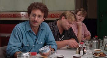 Movie still from “Reversal of Fortune” (1990), directed by Barbet Schroeder – A group of people sitting at a table with food; Medium shot, Over the shoulder angle
