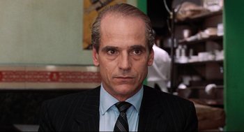 Movie still from “Reversal of Fortune” (1990), directed by Barbet Schroeder – A person wearing a suit and tie; Close Up shot, Low angle