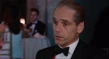 Movie still from “Reversal of Fortune” (1990), directed by Barbet Schroeder – A person wearing a suit and tie; Close Up shot, Over the shoulder angle
