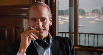 Movie still from “Reversal of Fortune” (1990), directed by Barbet Schroeder – A man smoking a cigarette while wearing a suit and tie; Close Up shot, Low angle