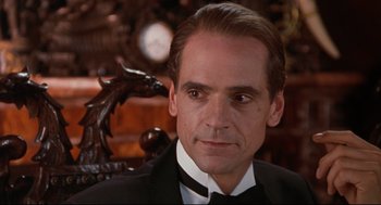 Movie still from “Reversal of Fortune” (1990), directed by Barbet Schroeder – A person wearing a suit and tie; Close Up shot, Over the shoulder angle