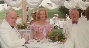 Movie still from “Reversal of Fortune” (1990), directed by Barbet Schroeder – A woman sitting at a table with a glass of wine in front of her; Medium shot, Over the shoulder angle
