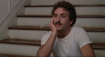 Movie still from “Reversal of Fortune” (1990), directed by Barbet Schroeder – A man sitting on the stairs with his hand under his chin; Close Up shot, Low angle