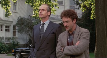 Movie still from “Reversal of Fortune” (1990), directed by Barbet Schroeder – A couple of men standing next to each other in front of a building; Medium shot, Low angle