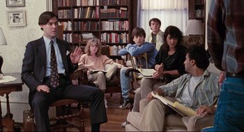 Movie still from “Reversal of Fortune” (1990), directed by Barbet Schroeder – A group of people sitting in a living room; Wide shot, Over the shoulder angle