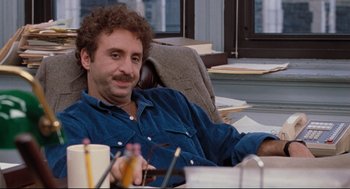 Movie still from “Reversal of Fortune” (1990), directed by Barbet Schroeder – A man sitting at a table with a cup of coffee; Medium shot, Over the shoulder angle