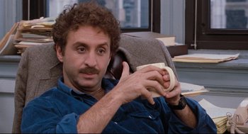 Movie still from “Reversal of Fortune” (1990), directed by Barbet Schroeder – A man sitting in a chair holding a banana; Close Up shot, Over the shoulder angle