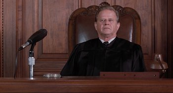 Movie still from “Reversal of Fortune” (1990), directed by Barbet Schroeder – A judge sitting in a court room with a judge's gavel in front of him; Medium shot, Low angle