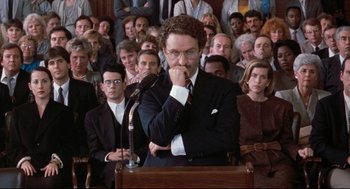 Movie still from “Reversal of Fortune” (1990), directed by Barbet Schroeder – A man that is giving a speech in front of a crowd; Medium shot, High angle