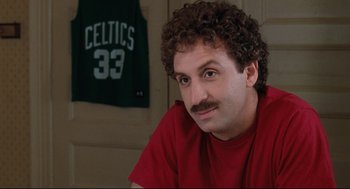 Movie still from “Reversal of Fortune” (1990), directed by Barbet Schroeder – A man with curly brown hair and a red t - shirt; Close Up shot, Over the shoulder angle
