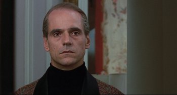 Movie still from “Reversal of Fortune” (1990), directed by Barbet Schroeder – A person wearing a suit and tie; Close Up shot, Over the shoulder angle