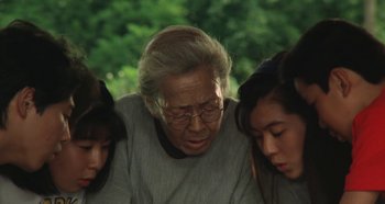 Movie still from “Rhapsody in August” (1991), directed by Akira Kurosawa – An old woman with two young girls sitting next to her; Close Up shot, Low angle