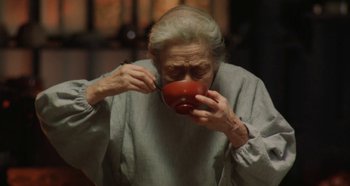 Movie still from “Rhapsody in August” (1991), directed by Akira Kurosawa – An older woman holding an apple up to her mouth; Close Up shot, High angle