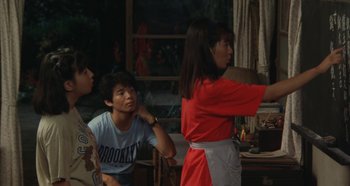 Movie still from “Rhapsody in August” (1991), directed by Akira Kurosawa – A group of people standing in a living room; Medium shot, Over the shoulder angle
